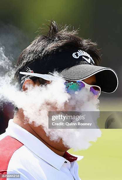 Kiradech Aphibarnrat of Thailand smokes an electric cigarette during day two of the World Cup of Golf at Kingston Heath Golf Club on November 25,...