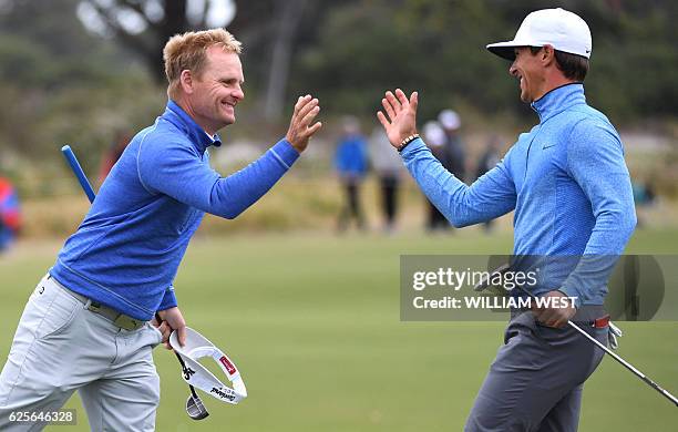 Soren Kjeldsen of Denmark and his teammate Thorbjorn Olesen shake hands after the second day of the World Cup of Golf on the Kingston Heath course in...