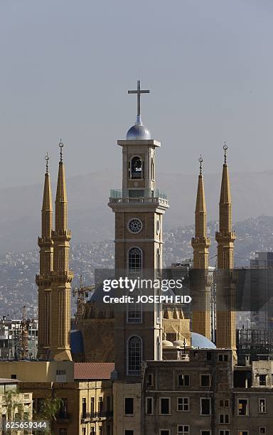 The newly built 72m bell tower of the Maronite Saint Georges cathedral is seen between the four minarets of Mohmmed al-Amin mosque in downtown...