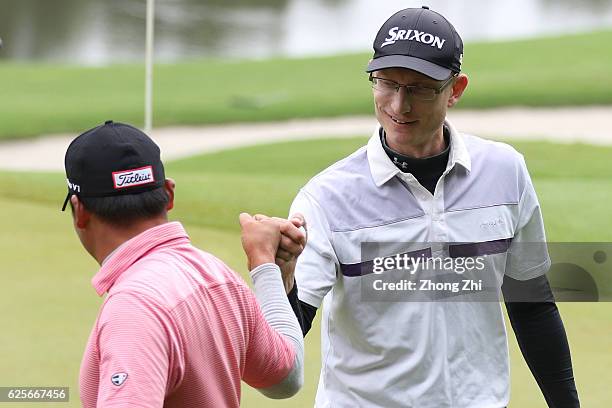 Mark Baldwin of the United States reacts with Guiming Liao of China during the second round of the Buick open at Guangzhou Foison Golf Club on...