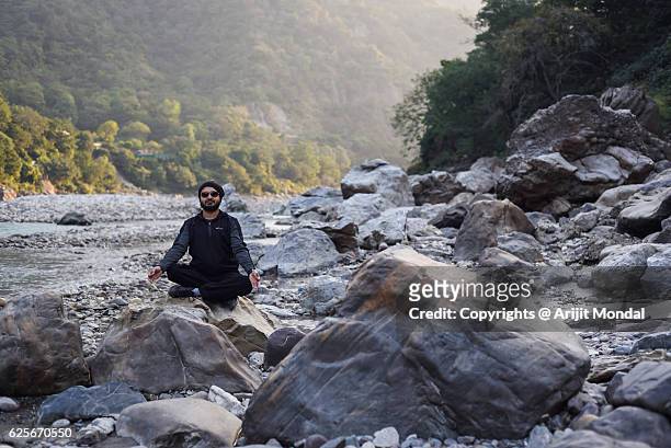 young man doing yoga exercises outdoors river bank of ganges - haridwar 個照片及圖片檔