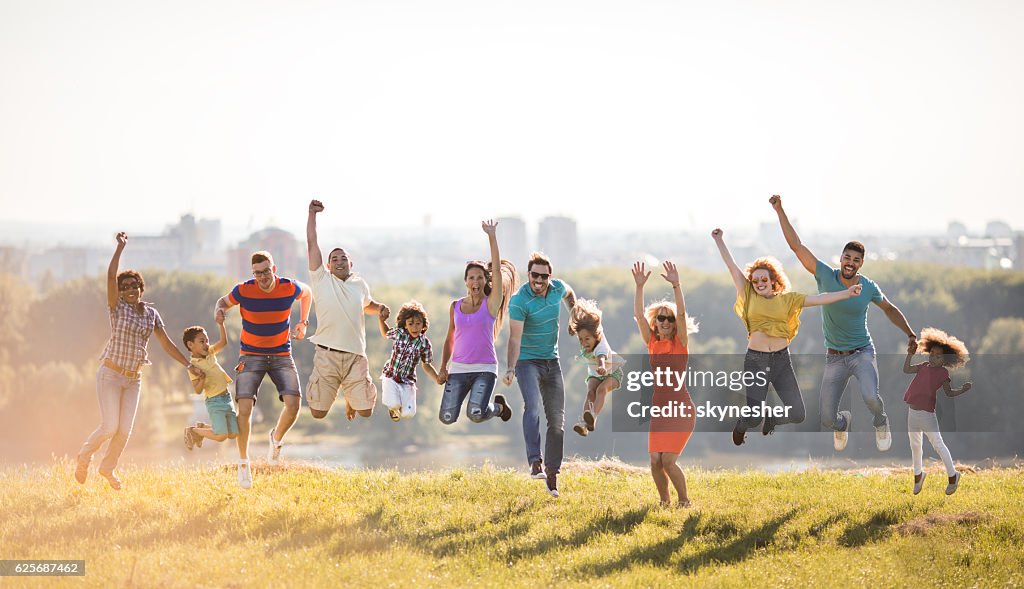 Grupo de personas felices saltando en la naturaleza con las manos levantadas.