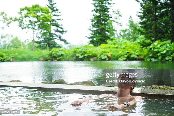 jovem desfrutando de água de fonte quente em hokkaido, japão - hokkaido japão - fotografias e filmes do acervo