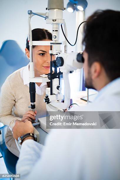 mujer joven con sus ojos examinados por optometrista. - optometrista fotografías e imágenes de stock