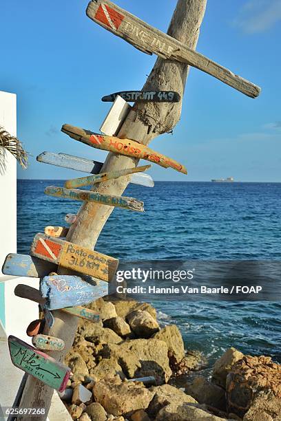 wooden sign board in front of sea - hannie van baarle stock pictures, royalty-free photos & images