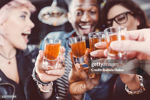 happy friends drinking shots - black shots cheers stockfoto's en -beelden