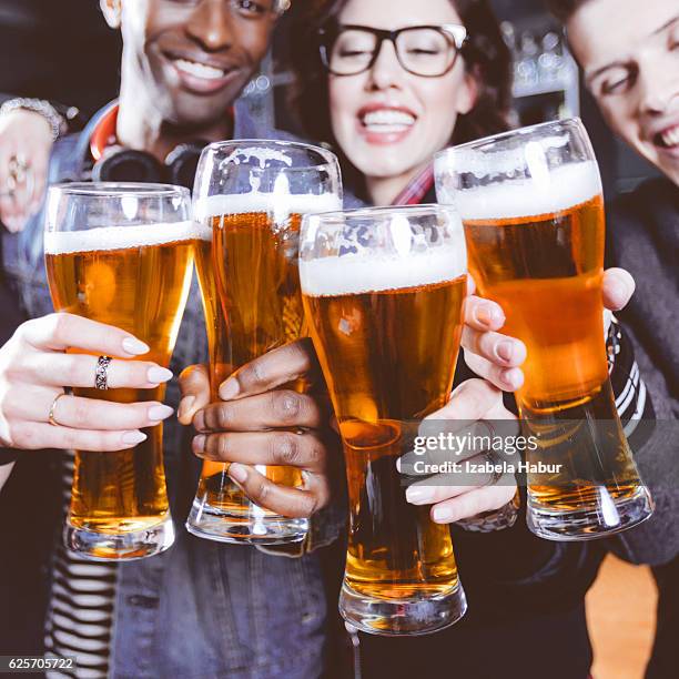 freunden anstoßen mit bier im pub - lagerbier stock-fotos und bilder