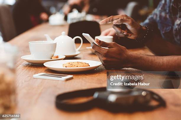 afro amercian man using smart phone in coffee shop - african american restaurant texting stockfoto's en -beelden