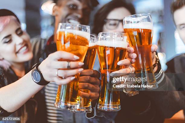 brindis de amigos con una cerveza en el bar - cerveza lager fotografías e imágenes de stock