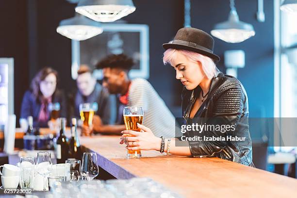 cool blond young woman drinking beer in a pub - cool man leather stock pictures, royalty-free photos & images
