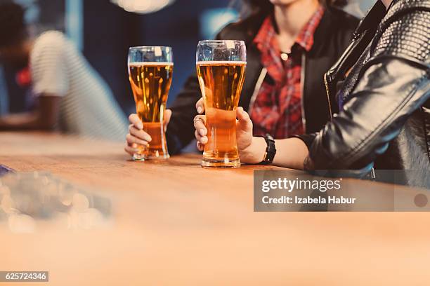 two cool girls drinking beer in a pub - beer glass hand stock pictures, royalty-free photos & images