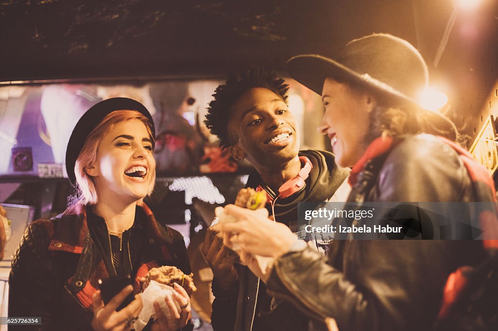 Multi ethnic friends eating burgers in pub