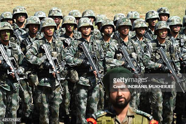 An Indian Army soldier stands in front of a group of People's Liberation Army of China soldiers as they line up after participating in an anti-terror...