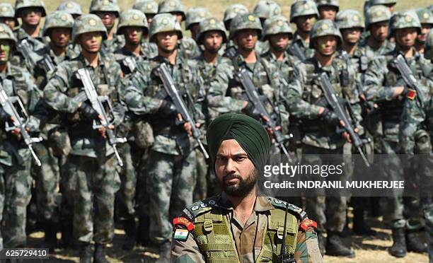 An Indian Army soldier stands in front of a group of People's Liberation Army of China soldiers as they line up after participating in an anti-terror...