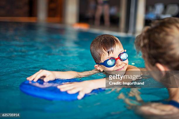 bambino durante lezione di nuoto in piscina al chiuso - nuoto foto e immagini stock