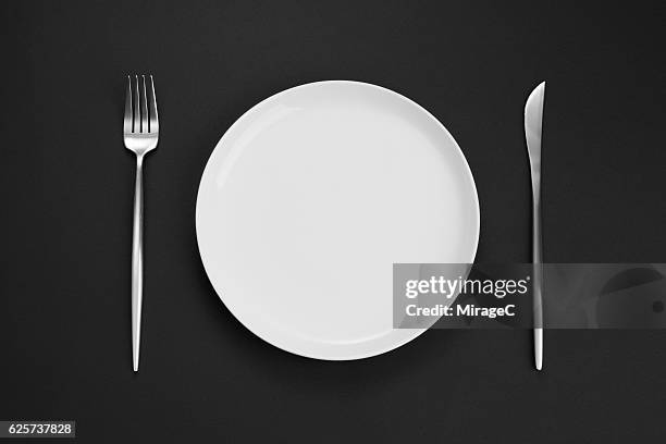 empty white plate with eating utensil - bestek stockfoto's en -beelden