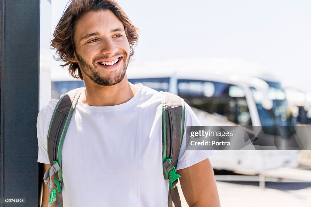 Homem sorridente olhando para o lado enquanto se inclinava na parede