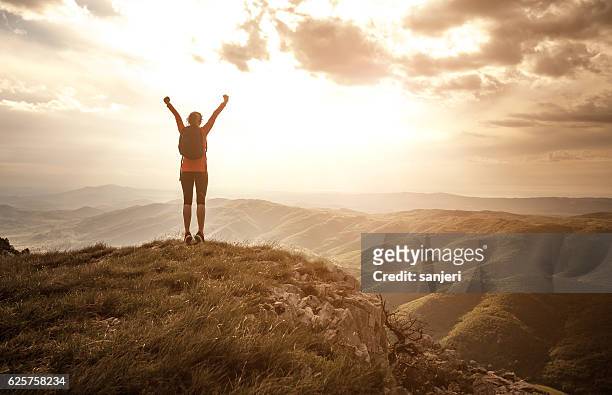 mujer saludando al sol en la cima de la colina - alzar los brazos fotografías e imágenes de stock