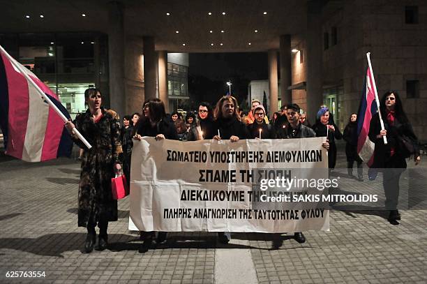 Demonstrators hold candles and a banner during a protest march for the International Transgender Day of Remembrance in Thessaloniki on November 25,...