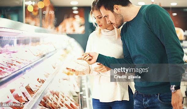 couple buying fresh meat in supermarket. - butchers shop stock pictures, royalty-free photos & images