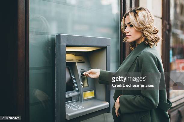 jeune femme à l'aide d'un distributeur automatique de billets - dab photos et images de collection