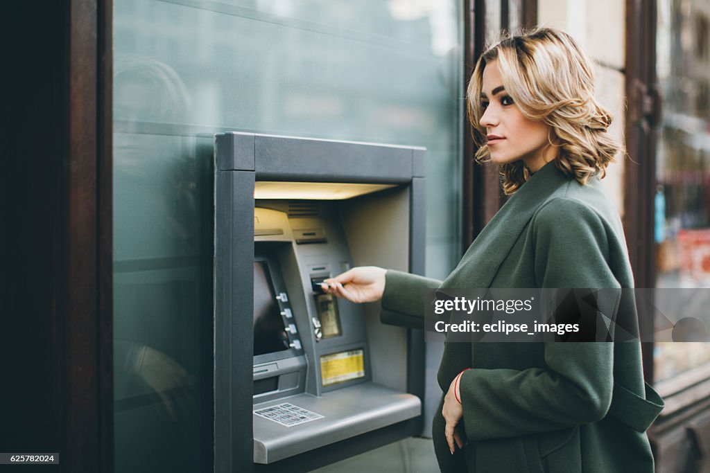 Young woman using ATM