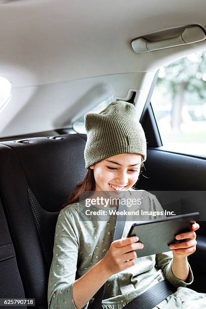 watching movies in the car with tablet - girl in car with ipad stock pictures, royalty-free photos & images