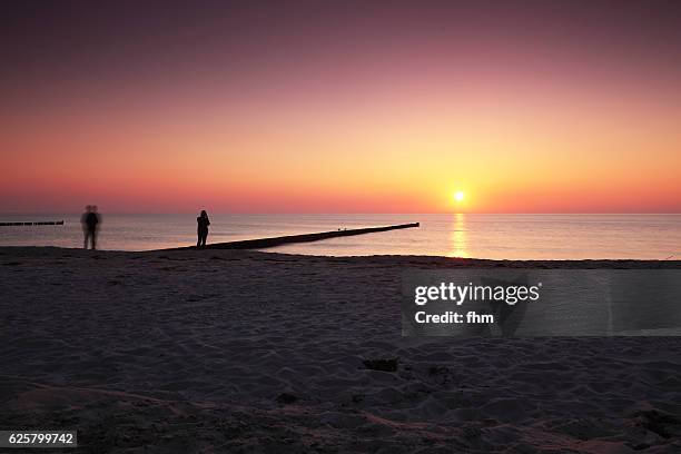 sunset on the beach with two people - sunset beach 個照片及圖片檔