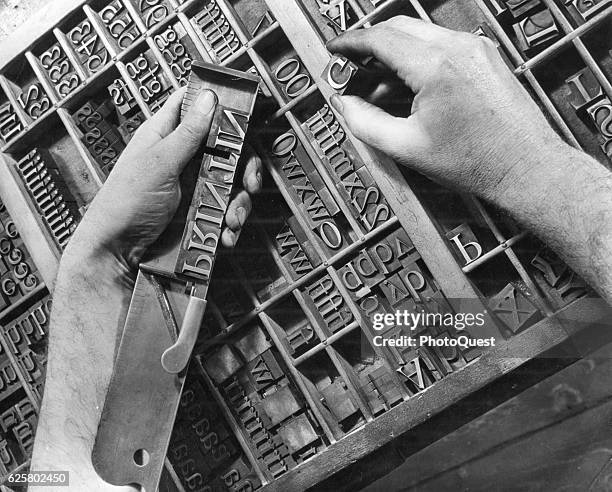 Close-up show the hands of a printer who composes a 'stick' of large type, 1951.