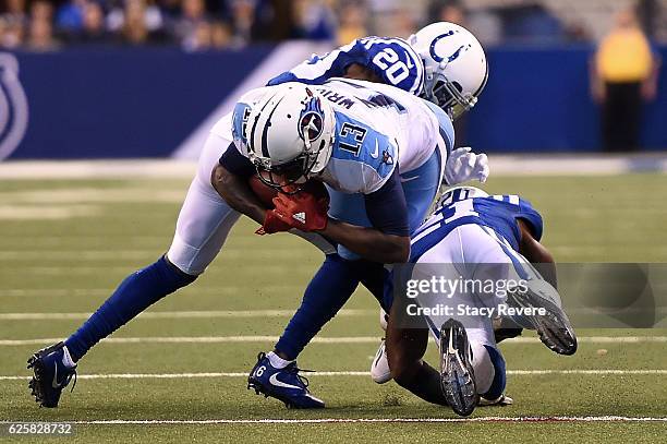 Kendall Wright of the Tennessee Titans is brought down by Darius Butler and Vontae Davis of the Indianapolis Colts during a game at Lucas Oil Stadium...