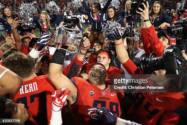 Defensive lineman Sani Fuimaono of the Arizona Wildcats celebrates with the Territorial Cup after defeating the Arizona State Sun Devils 56-35 in...