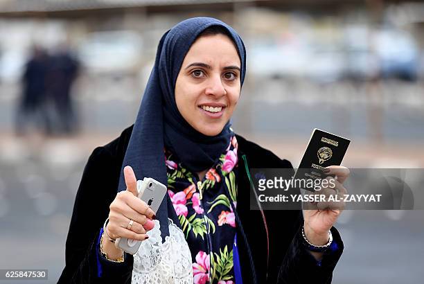 Kuwaiti woman holds her passport as she arrives to cast her vote at a polling station in Kuwait City, on November 26, 2016. Polls opened in Kuwait...