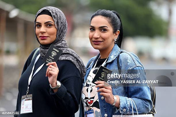 Kuwaiti women flash their passports as they arrive to cast their votes at a polling station in Kuwait City, on November 26, 2016. Polls opened in...