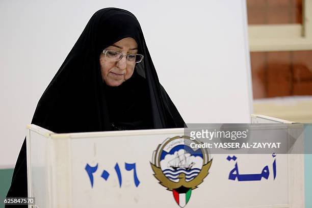 Kuwaiti woman writes on her ballot paper before casting her vote for the parliamentary elections at a polling station in Kuwait City on November 26,...