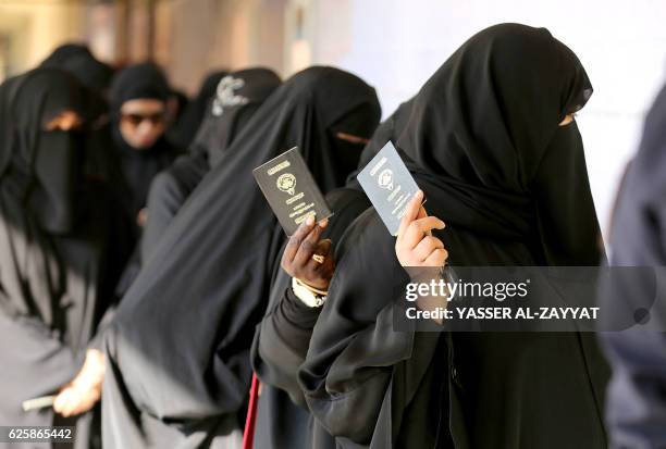 Kuwaiti women show their passports as they arrive at a polling station to cast their votes for the parliamentary elections in Kuwait City on November...