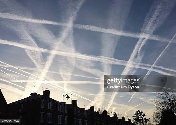 APRIl 12: A pattern of condensation trails, otherwise known as contrails - produced by aircraft engine exhausts, criss-cross the sky at sunrise above...