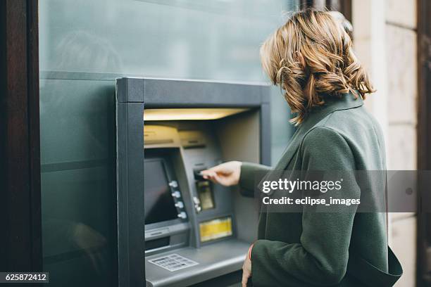 young woman using atm - bank financieel gebouw stockfoto's en -beelden