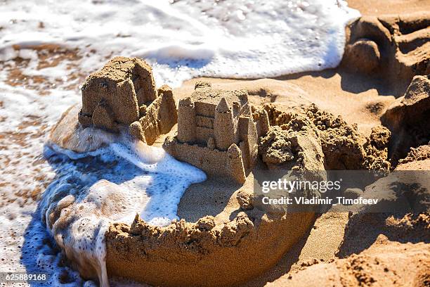 waves wash away sand castles on beach the sea