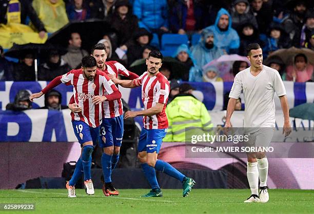 Sporting Gijon's midfielder Carlos Carmona celebrates a goal with teammates beside Real Madrid's midfielder Lucas Vazquez during the Spanish league...