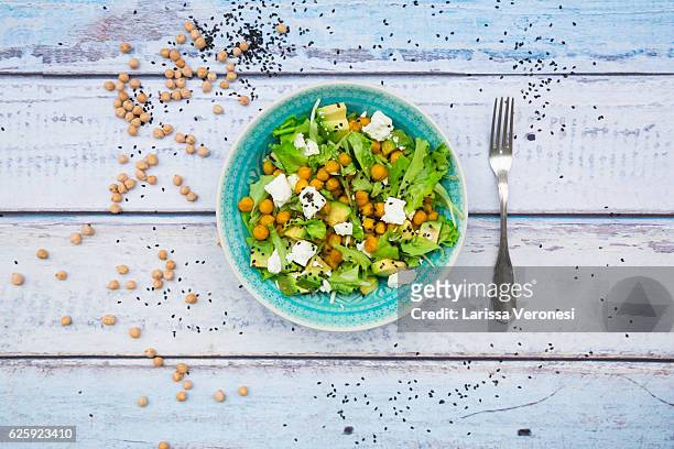 mixed raw salad with roasted chickpeas, feta cheese, avocado and black sesame on plate - chick pea salad stock pictures, royalty-free photos & images