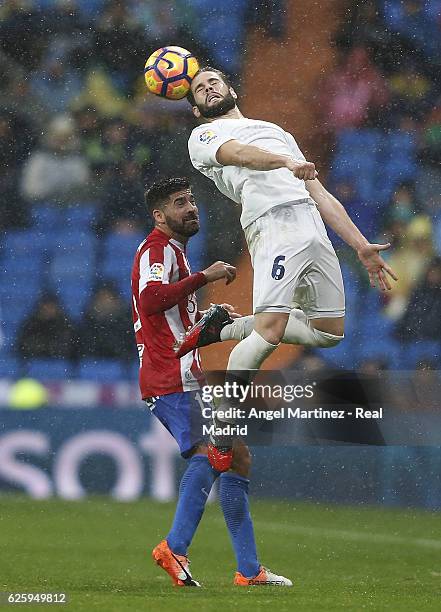 Nacho Fernadez of Real Madrid heads the ball under pressure from Carlos Carmona of Real Sporting de Gijon during the La Liga match between Real...