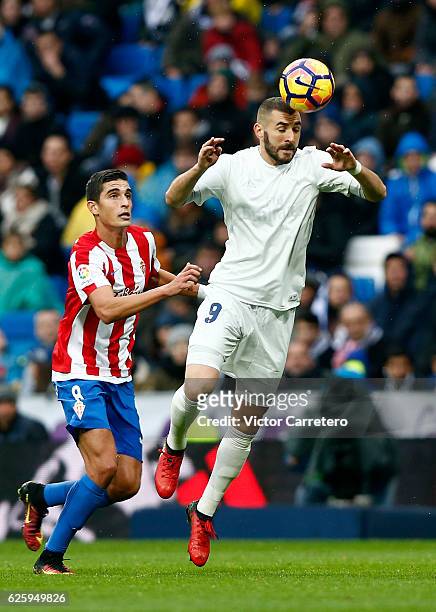 Karim Benzema of Real Madrid heads the ball next to Rachid Ait-Atmane of Sporting de Gijon during the La Liga match between Real Madrid CF and Real...