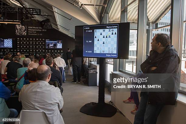 Fans watch a live feed broadcast of Sergey Karjakin, Russian chess grandmaster, playing against Magnus Carlsen, Norwegian chess grandmaster and...