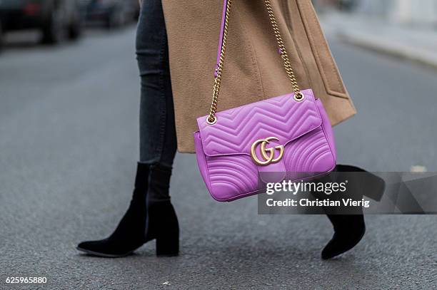 Sonia Lyson wearing black Lala Berlin velvet ankle boots, black Levis pants, a navy Rad sweater with print, a beige Max Mara camel hair coat, pink...