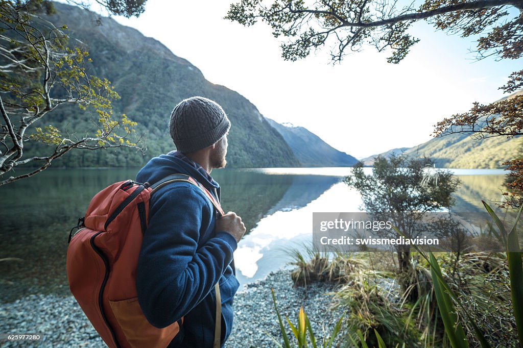 L’homme voyageur au bord du lac de montagne contemple un beau paysage