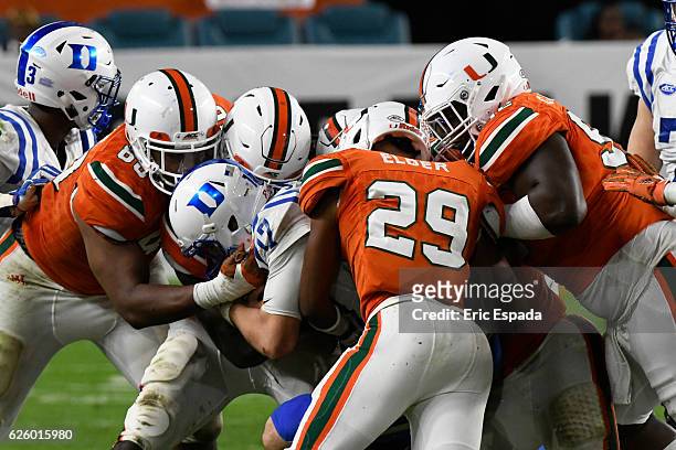 Daniel Jones of the Duke Blue Devils is tackled by Corn Elder, RJ McIntosh, and Courtel Jenkins of the Miami Hurricanes during the 3rd quarter of the...