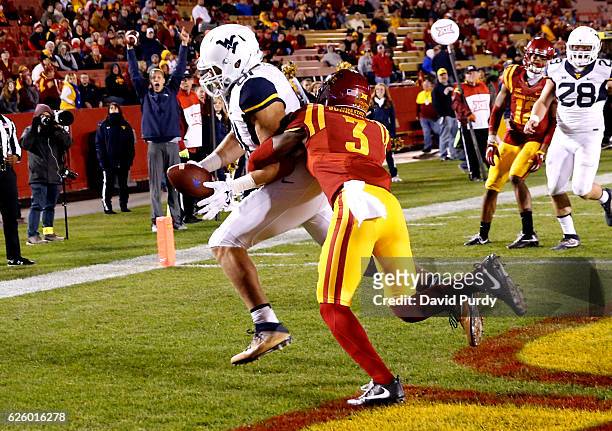 Tight end Trevon Wesco of the West Virginia Mountaineers pulls in the ball for a touchdown as defensive back Mike Johnson of the Iowa State Cyclones...