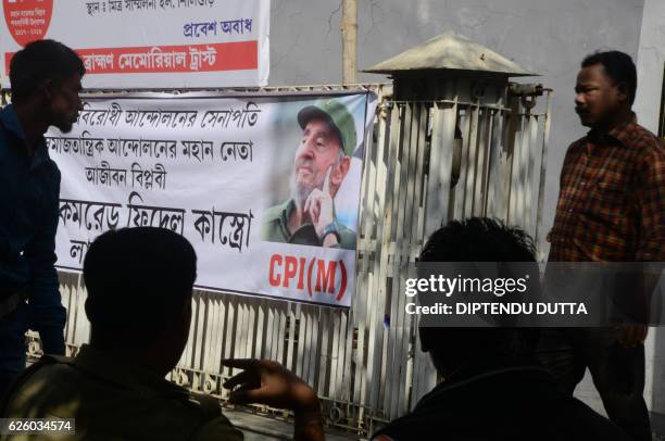 Indian residents sit near a banner displaying the image of former Cuban president Fidel Castro in Siliguri on November 27, 2016. - Cuba's historic...