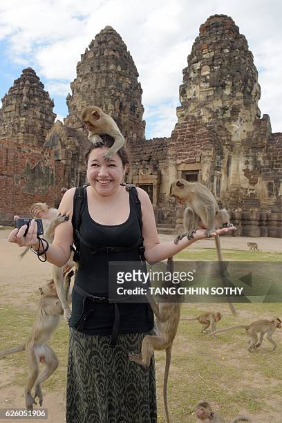 Monkeys jump up on tourist Katie Myers from the US at an ancient temple during the annual "monkey buffet" in Lopburi province, north of Bangkok on...