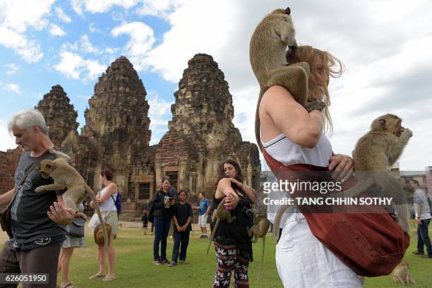 Monkeys jump up onto tourists at an ancient temple during the annual "monkey buffet" in Lopburi province, north of Bangkok on November 27, 2016. It...